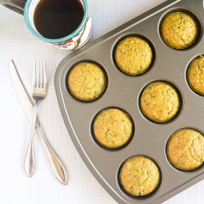 Top view of spinach almond amaranth breakfast muffins in the muffin tray along with a cup of coffee