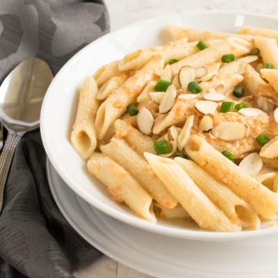 A 45 degree angle view of penne in carrot sauce