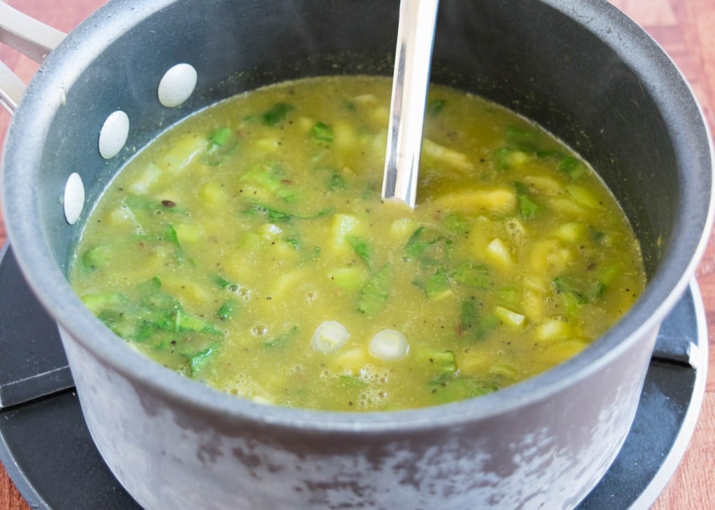 a saucepan with the soup in it it and a spatula to stir.