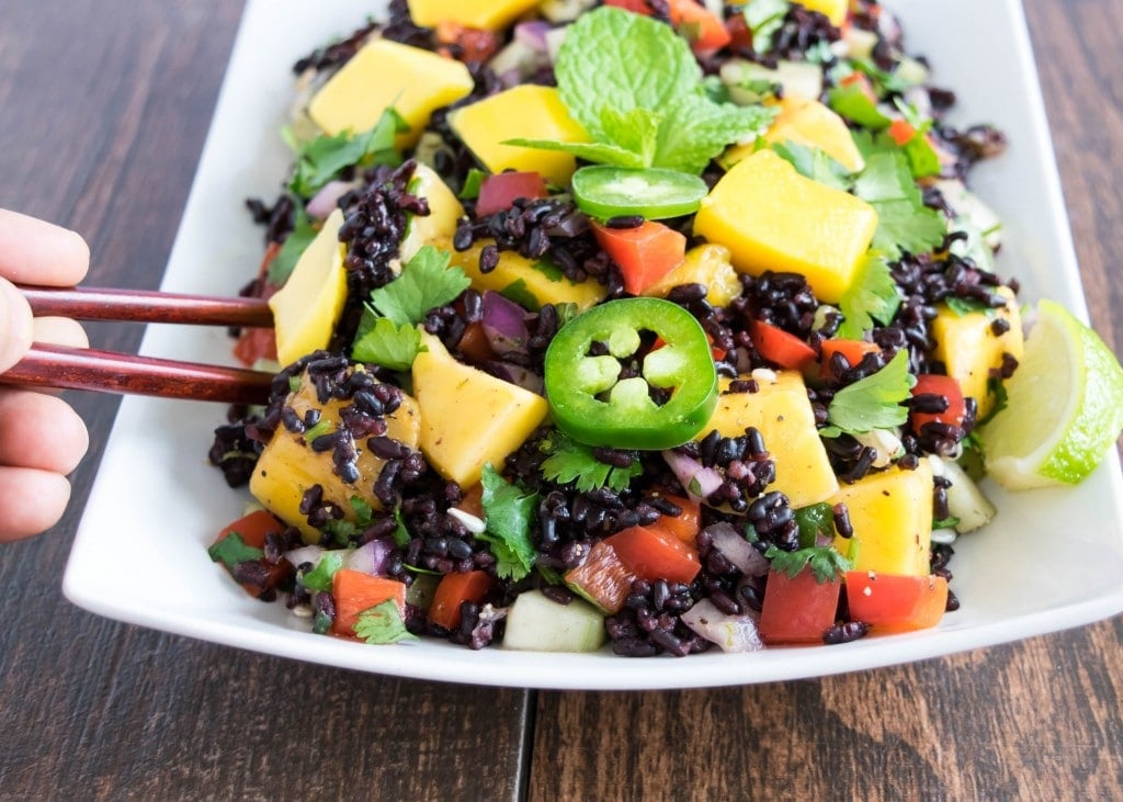 A chopstick picking up salad from the plate