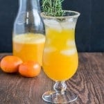 A glass filled with orange thyme mocktail