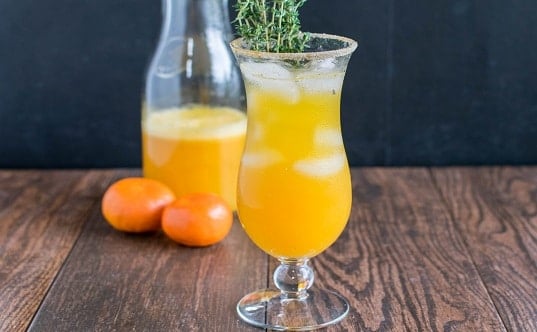 A glass filled with orange thyme mocktail