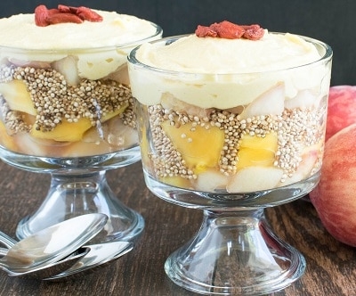 A close up view of roasted peaches, puffed quinoa and papaya cashew cream parfait