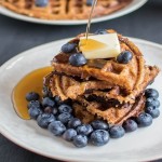 Syrup pouring over stacked peanut butter bulgur waffles