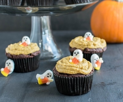 Chocolate Almond Cupcakes with Pumpkin Frosting on the table along with a cake stand in the background loaded with the cupcakes