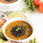 A front view of Herbed Black Rice Soup with the raw ingredients at the backdrop