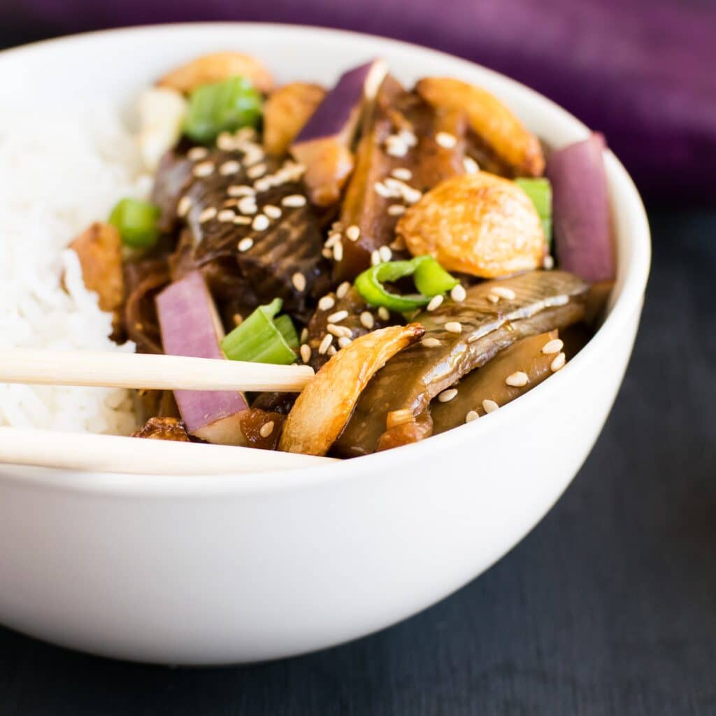 a chopstick picking up burnt garlic eggplant