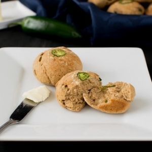 garlic jalapeno oatmeal rolls on a serving plate with a butter knife