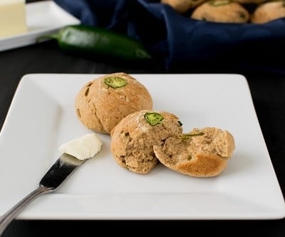 garlic jalapeno oatmeal rolls on a serving plate with a butter knife