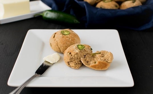garlic jalapeno oatmeal rolls on a serving plate with a butter knife