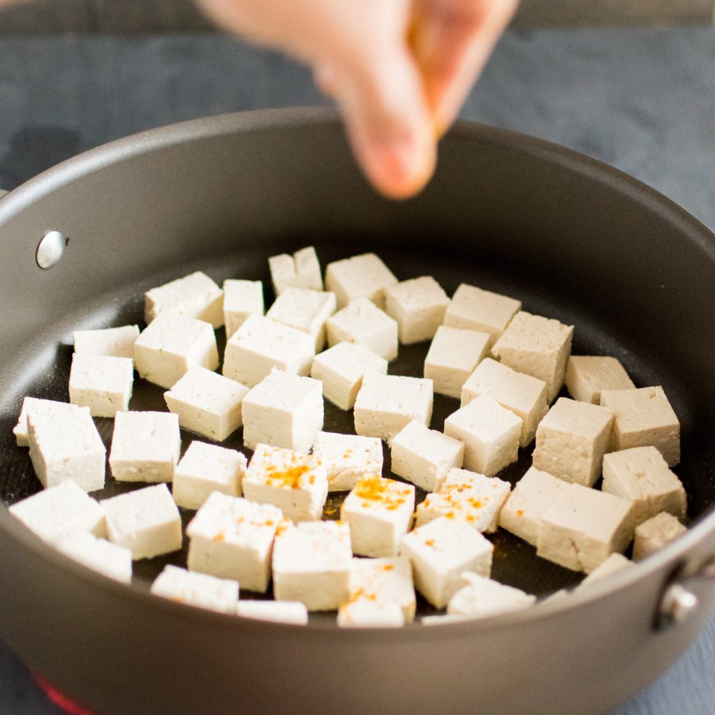 Sprinkling of masala on tofu is shown