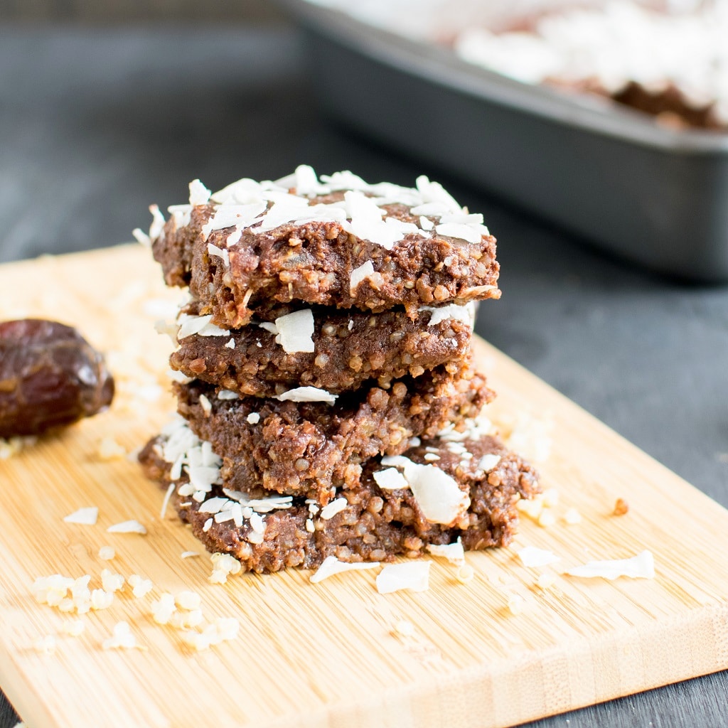 A front view of a stack of No Bake Chocolate Coconut Quinoa Brownies on a wooden board