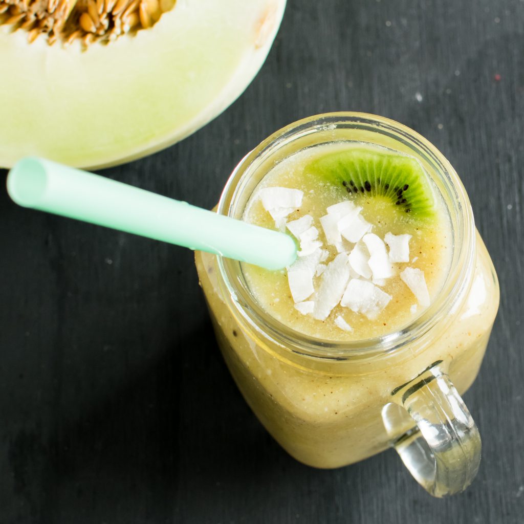 A closer top view of kiwi Honeydew Coconut Smoothie with coconut flakes and sliced kiwi as the garnishing is shown.