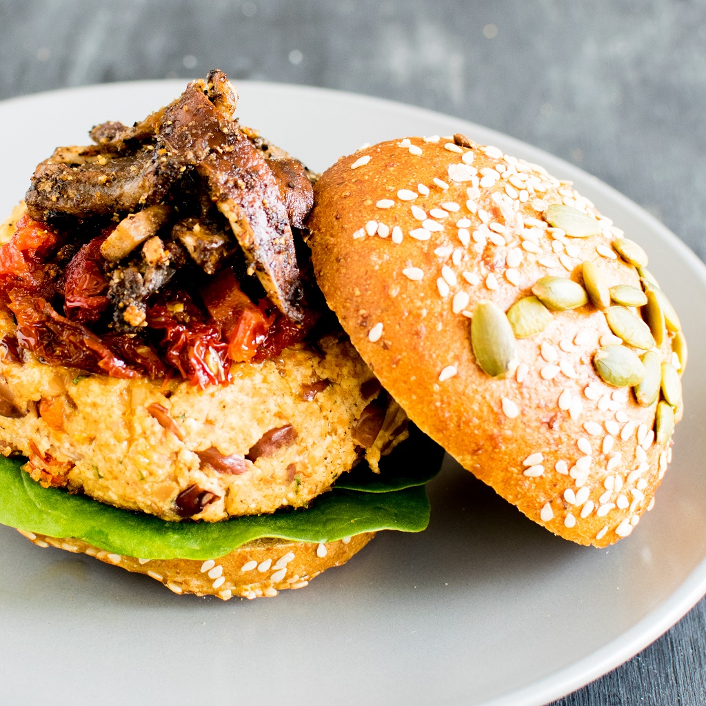 A 45 degree angle view of Tofu Kidney Beans Sun Dried Tomato Burger with Sauteed Mushrooms 
