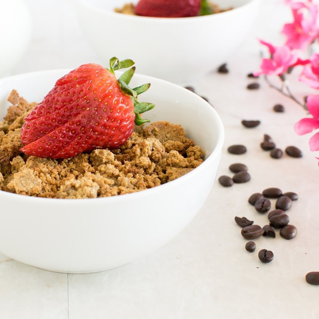 Coffee Cheesecake Quinoa Granola Clusters in a breakfast bowl with a strawberries on the top