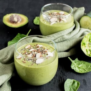 Super green Smoothie is shown in serving glasses with the ingredients as the prop