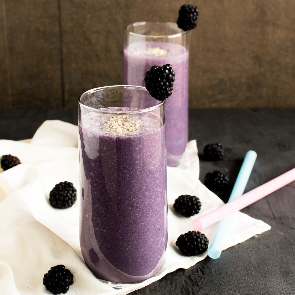 Antioxidant Blackberry Smoothie is shown in the serving tall serving glasses with blackberries as the prop for the image.