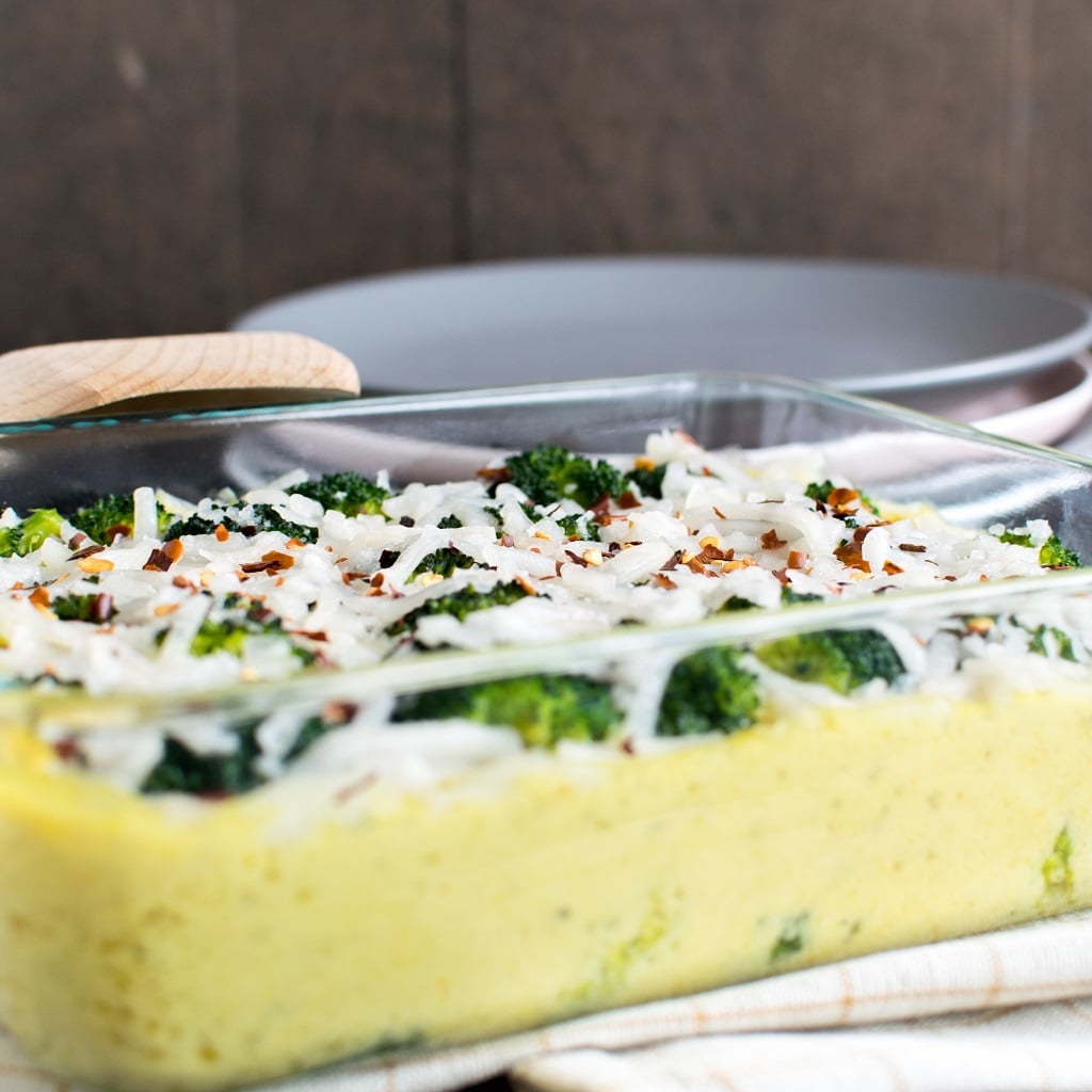 Baked Cheese Broccoli Vegan Casserole with a spatula and lots of plates as the prop.