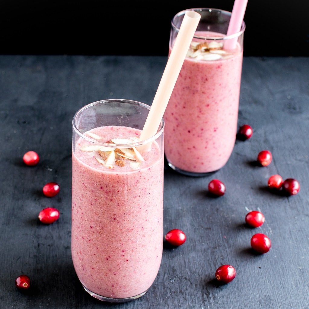 Cranberry Amaranth Smoothie shown in two tall glasses with straws in it. 