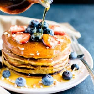 a front view of stacked vegan chickpea flour pancakes with maple syrup drizzling over them.