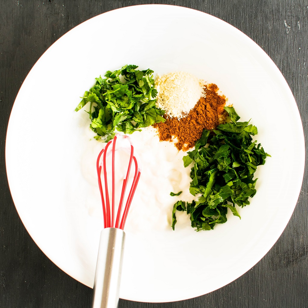 The ingredients of the marinade in a white bowl with a whisk is shown in this image. 