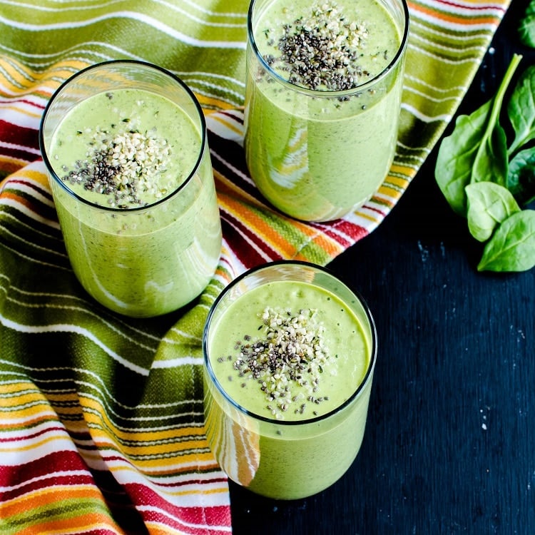 A top view of the table spread with smoothie glasses filled with Chia Hemp Green Smoothie and raw ingredients as prop is shown in this image.