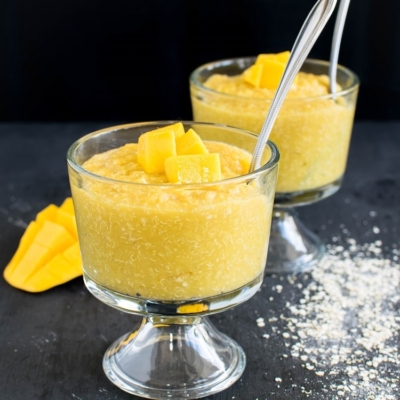 The chilled 4 ingredient quinoa flakes mango pudding in shown in serving glasses with the spoons dipped in them.