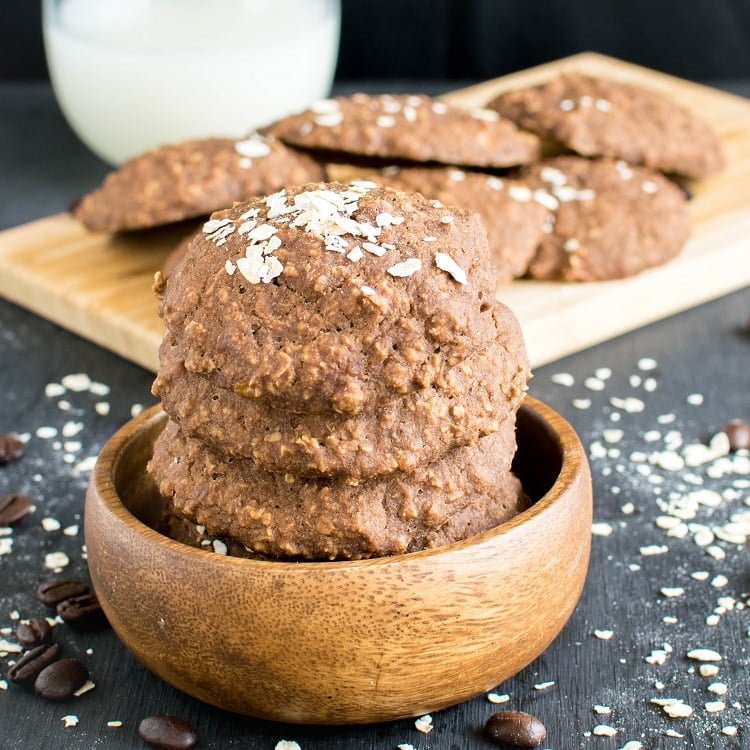 A big stack of vegan mocha oatmeal cookies in a wooden bowl is shown in this image.