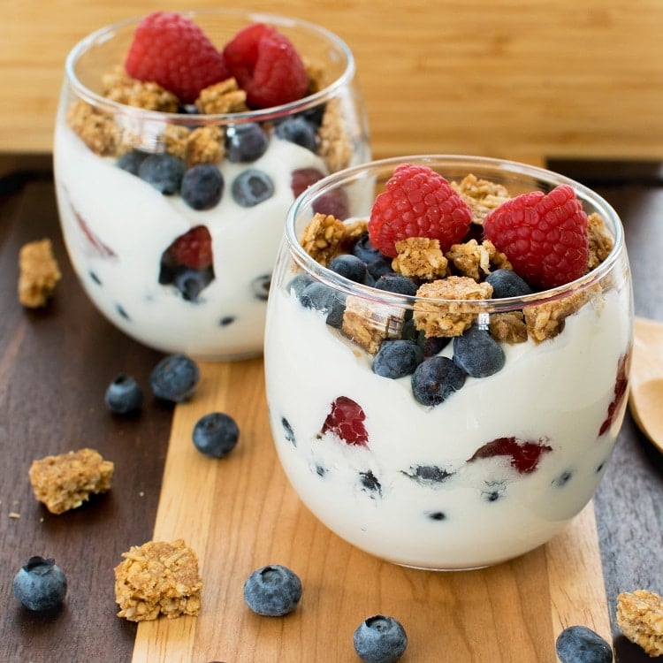 Healthy Breakfast Vegan Yogurt Parfait is displayed in 2 serving glasses with a wooden background.
