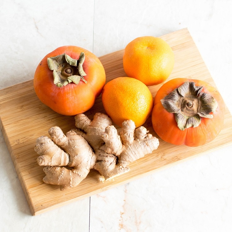 All the ingredients of Immune Boosting Persimmon Ginger Smoothie are shown on a wooden board