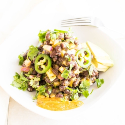 Vegan Papaya Black Bean Salad in a white bowl with a fork as the prop