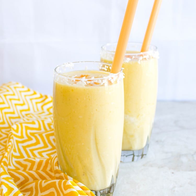 A front view of two tall glasses filled with Tropical Coconut Turmeric Smoothie.