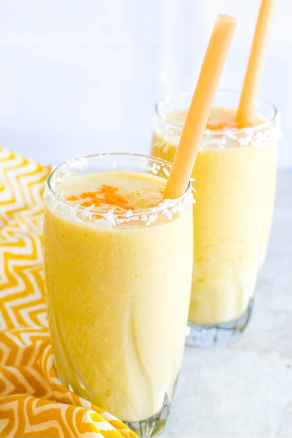 Tropical Coconut Turmeric Smoothie in two tall glasses with straws 