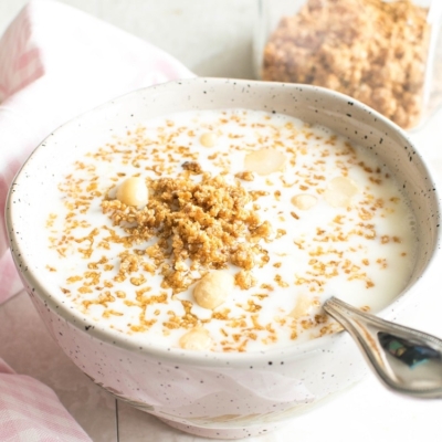 A 45 degree angle of vegan White Chocolate Quinoa Granola with milk in a breakfast bowl