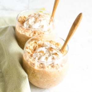 Two jars filled with Carrot Cake Vegan Overnight Oats and topped with coconut whipped cream