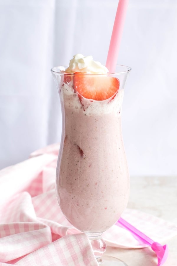 Vegan Strawberry Shortcake Protein Smoothie in a tall glass with a straw and a spoon