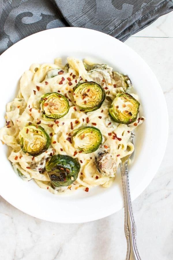 Roasted Brussel Sprouts Fettuccine Alfredo in a white serving dish with a fork