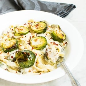 A 45 degree angle view of Roasted Brussel Sprouts Fettuccine Alfredo with a fork as a prop