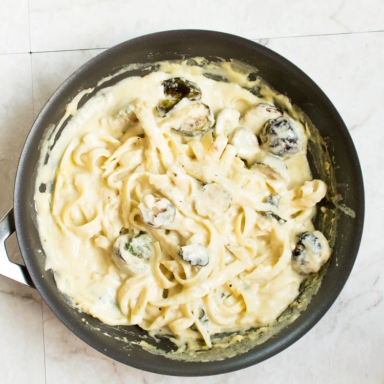 Roasted Brussel Sprouts stirred in Fettuccine Alfredo in a nonstick pan
