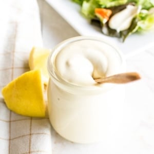 A glass container with Oil Free vegan Mayo and salad at the background