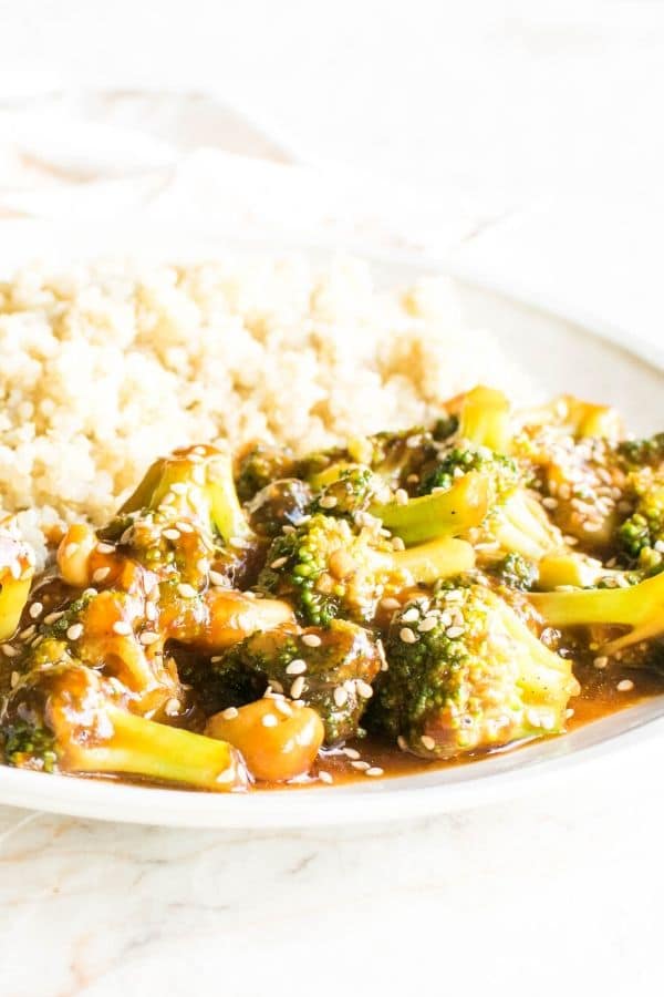 A close up front view of spicy cashew broccoli stir fry along with cooked quinoa on the side