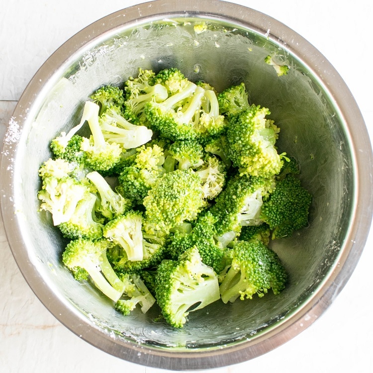 Broccoli and cornstarch mixed in a mixing bowl