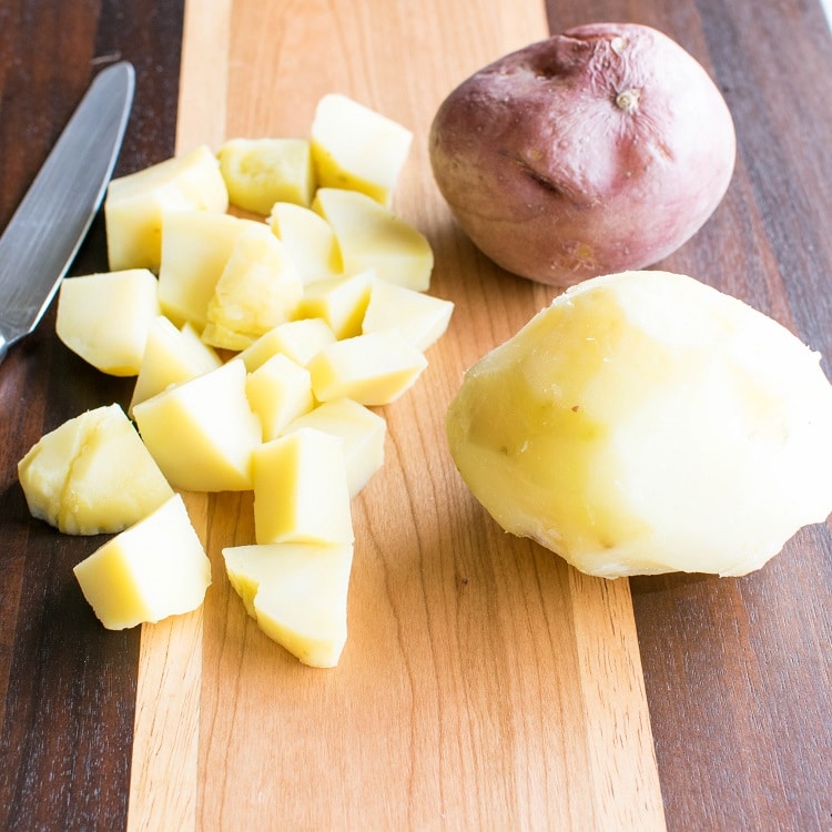 peeled and chopped potatoes on a wooden board