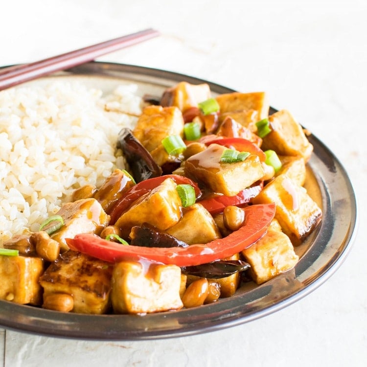 Kung Pao Tofu served with brown rice with chopsticks