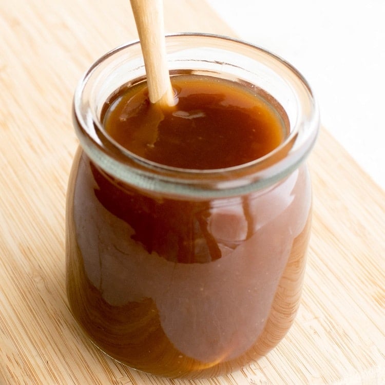 A close up view of sweet and sour sauce in a glass jar