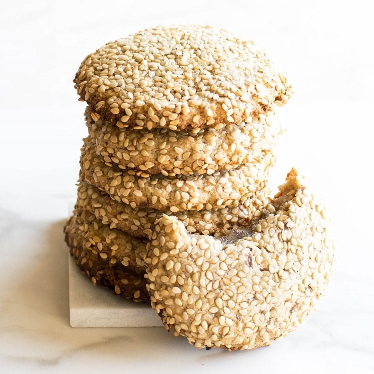 stacked one bowl tahini cookies with an eaten cookie on the side