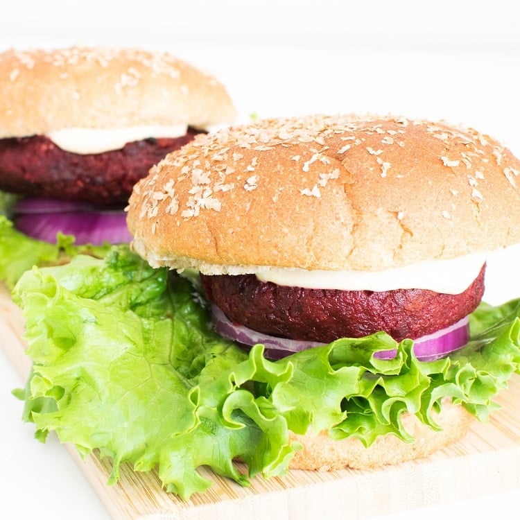 front view of 2 spicy beet burger on a wooden board