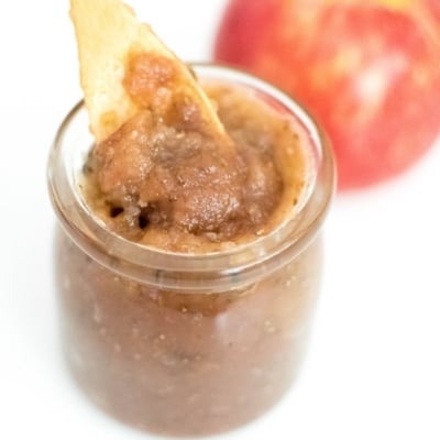 A spoon dipping in apple jam recipe jar