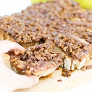 A hand picking up pear stuffed pecan sticky buns