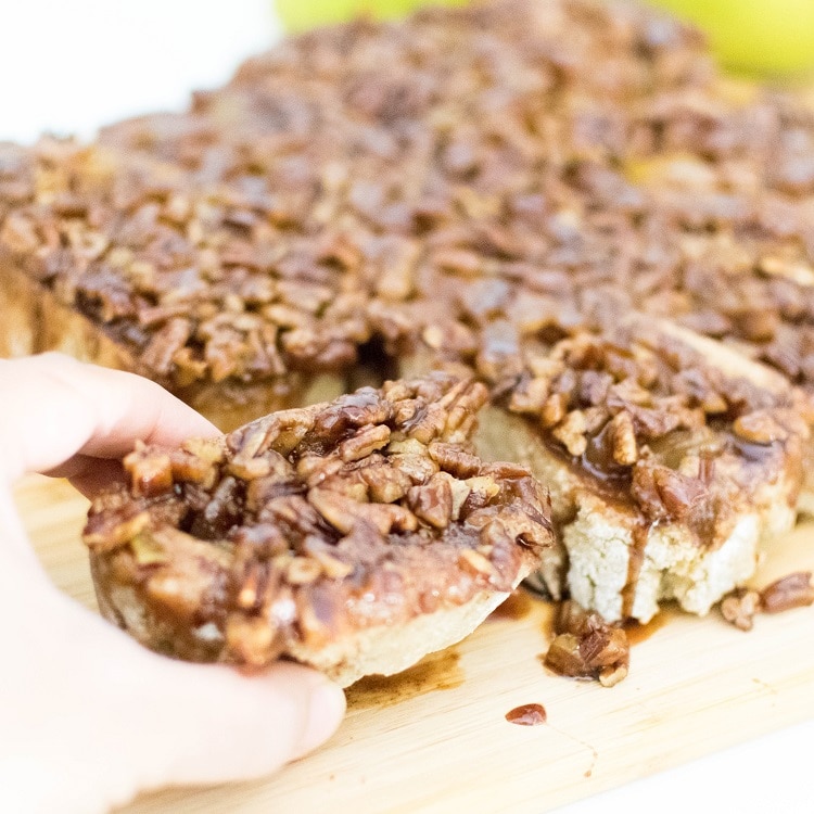 A hand picking up pear stuffed pecan sticky buns